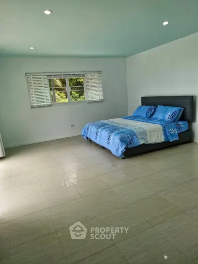 Spacious bedroom with tiled floor and large window in modern home