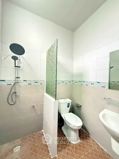 Modern bathroom with shower and toilet in a bright, tiled space.
