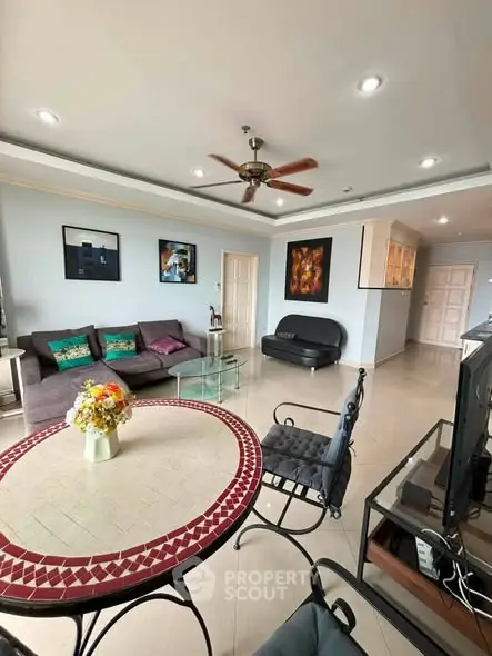 Spacious living room with modern decor and ceiling fan, featuring a cozy seating area and stylish dining table.