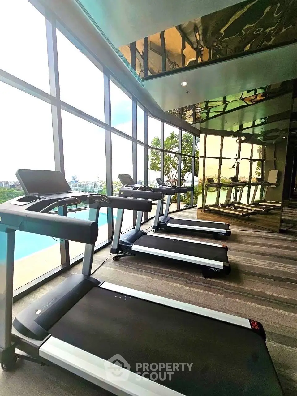 Modern gym with treadmills and panoramic city view in luxury real estate property.