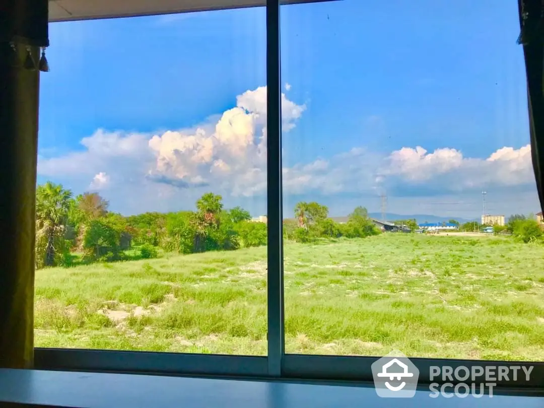 Serene view from a modern property showcasing a vast expanse of greenery under a bright blue sky, ideal for nature lovers seeking tranquility.