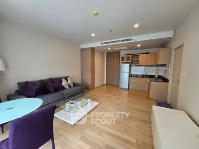 Modern open-layout living room with kitchen, featuring hardwood floors and stylish furniture.