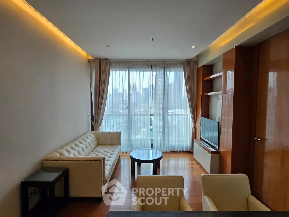 Modern living room with city view, featuring elegant furniture and floor-to-ceiling windows.