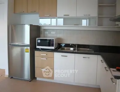 Modern kitchen with stainless steel fridge and microwave, sleek cabinetry, and dual sink.