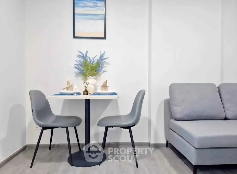 Modern living room with cozy gray sofa and stylish dining area for two, perfect for urban living.