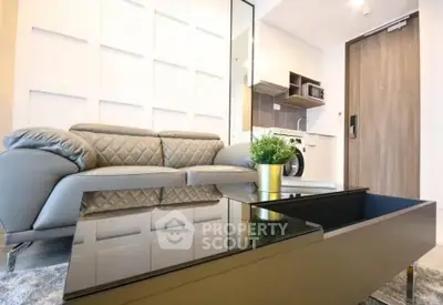 Modern living room with sleek furniture and compact kitchen in a stylish apartment.