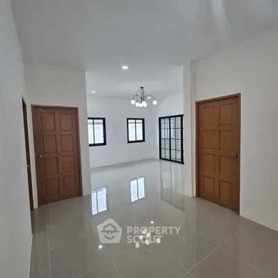 Spacious modern interior with glossy tile flooring and stylish lighting, perfect for versatile living space.