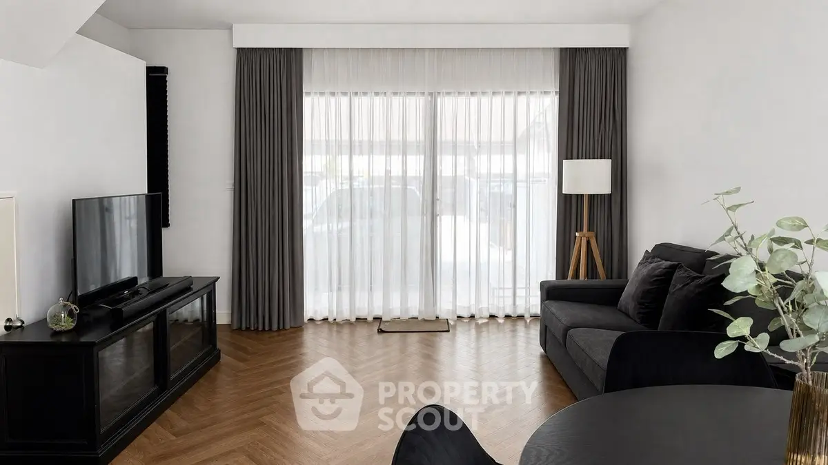 Elegant living room with modern decor, featuring a cozy sofa, stylish TV stand, and large window with curtains.