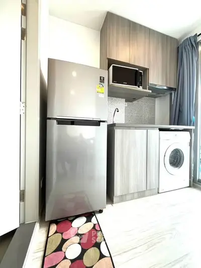 Modern kitchen with sleek appliances including fridge, microwave, and washing machine in compact layout.