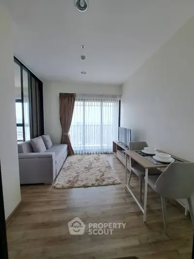 Modern living room with cozy sofa, dining table, and large window offering city views.