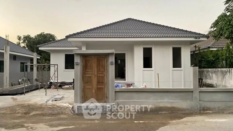Modern single-story house with tiled roof and spacious front yard under construction.