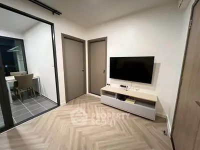 Modern living room with sleek TV setup and stylish flooring, adjacent to a cozy dining area with city view.