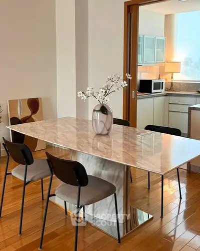 Elegant dining area with marble table and modern kitchen in open layout apartment.