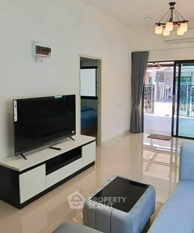 Modern living room with sleek furniture and large sliding glass doors leading to a balcony.