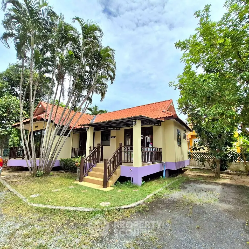 Charming single-story home with red roof and lush garden in tropical setting.