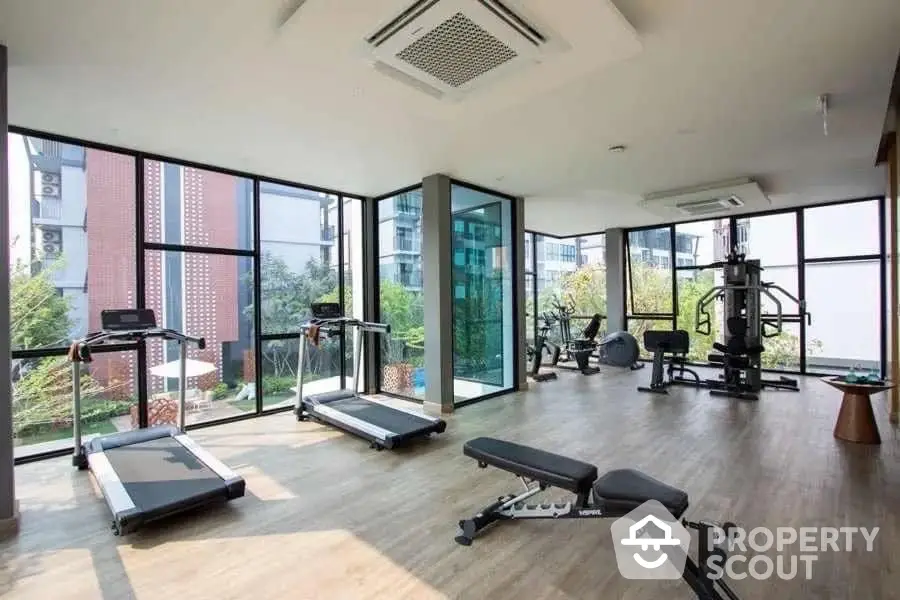 Modern gym with large windows and fitness equipment in luxury apartment building.