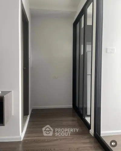 Modern hallway with sleek glass doors and wooden flooring in a contemporary apartment.