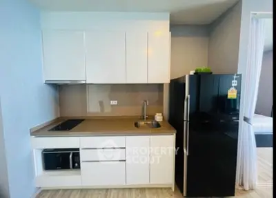 Modern kitchen with sleek cabinetry and black refrigerator in a stylish apartment.