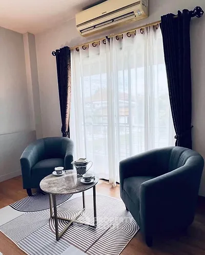 Cozy living room with elegant armchairs and a coffee table by large window.