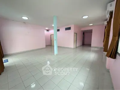 Spacious open-plan living area with tiled flooring and pastel pink walls, ideal for customization.
