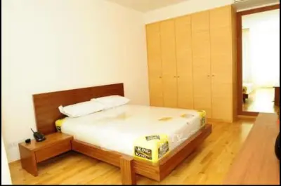 Spacious bedroom with wooden flooring and large wardrobe in modern apartment.