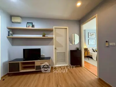 Modern living room with sleek TV stand and open shelving, leading to a cozy bedroom.