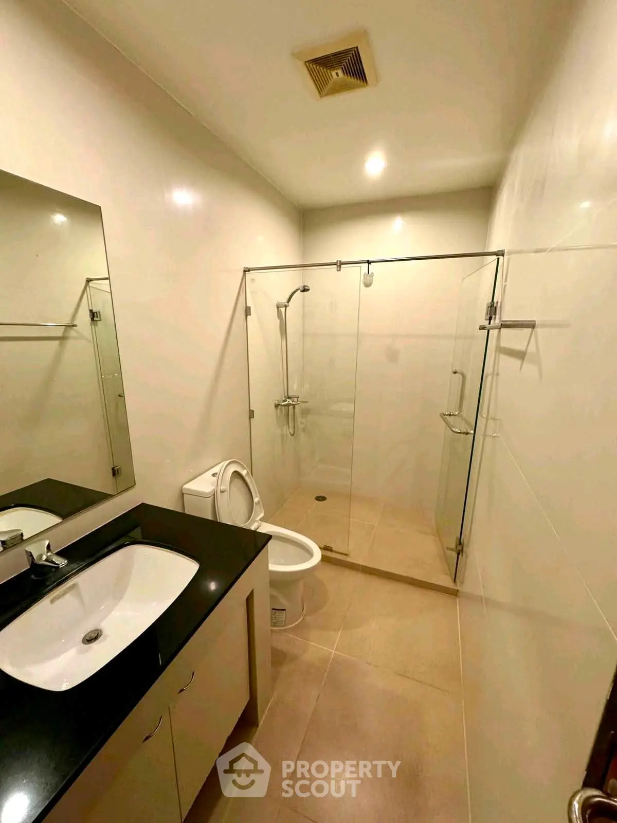 Modern bathroom with glass shower enclosure and sleek vanity in a contemporary apartment.