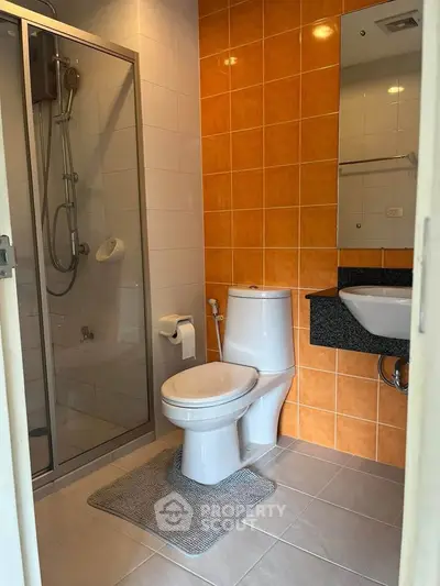 Modern bathroom with glass shower and orange tile accent wall