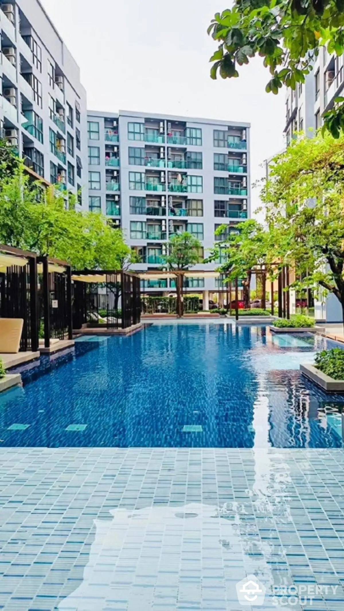 Luxurious condominium with stunning pool and lush greenery in modern urban setting.