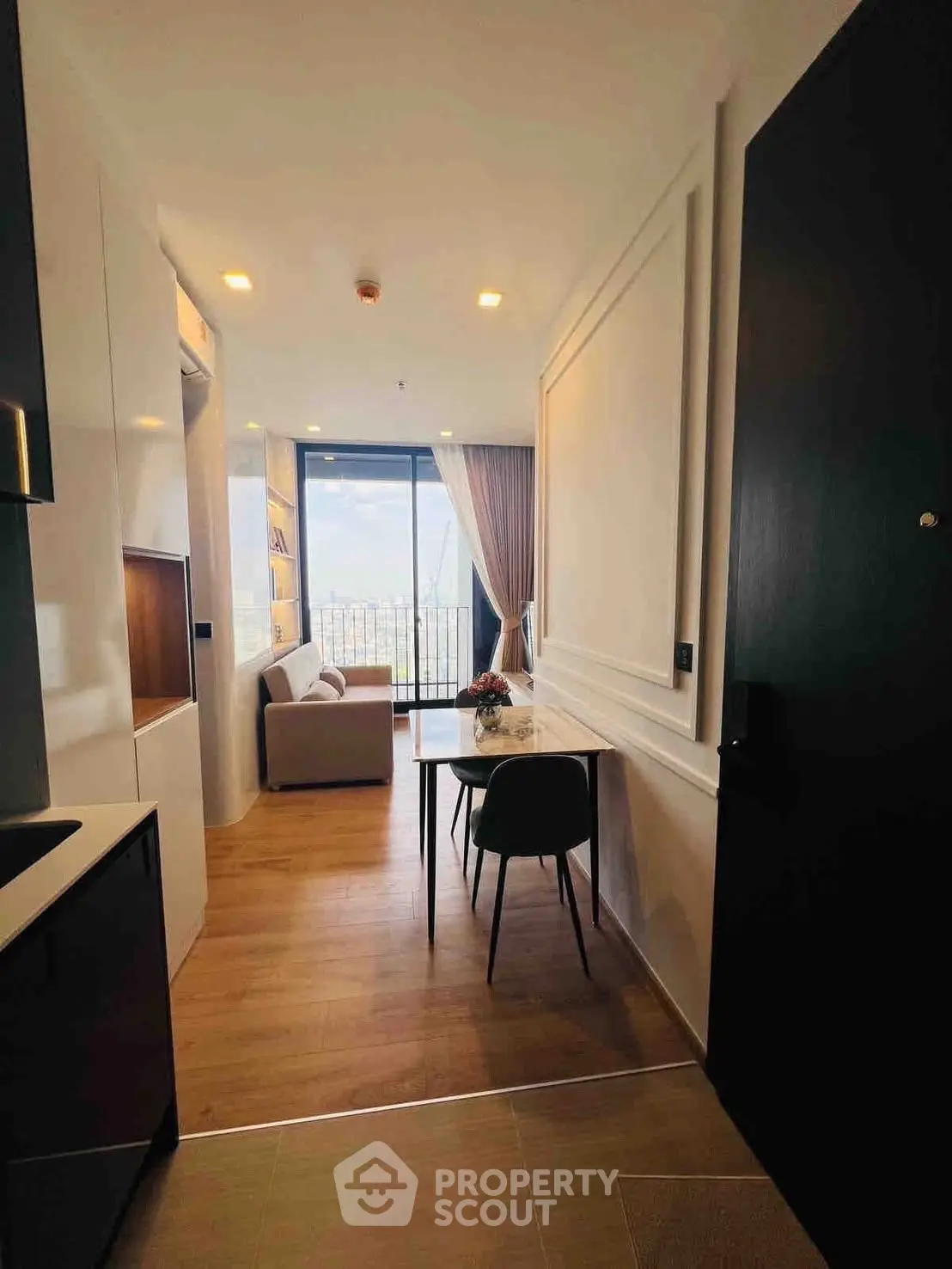 Modern apartment interior with open layout, featuring a cozy living area and stunning city view.