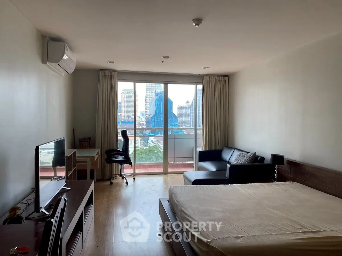 Modern studio apartment with city view, featuring a cozy bed, sofa, and workspace.