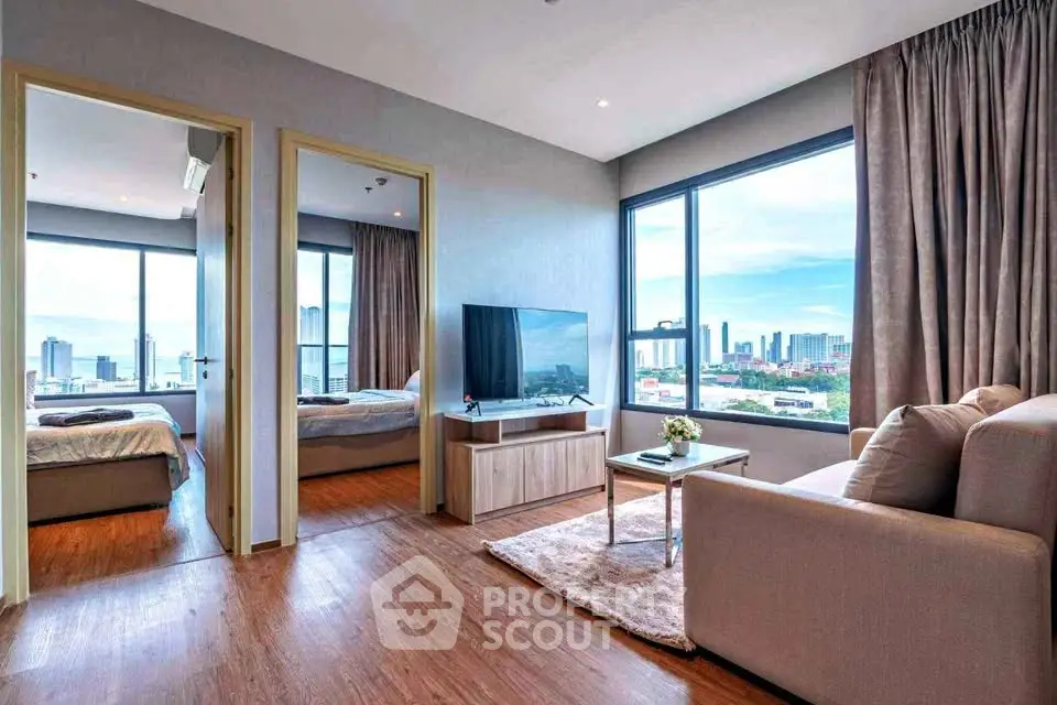 Modern living room with city view, featuring cozy seating and large windows for natural light.