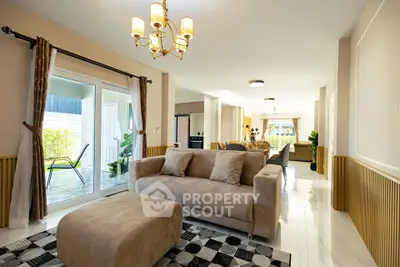Spacious living room with elegant decor and large windows opening to a patio, perfect for modern living.