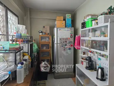 Compact kitchen with fridge, shelves, and appliances in cozy apartment
