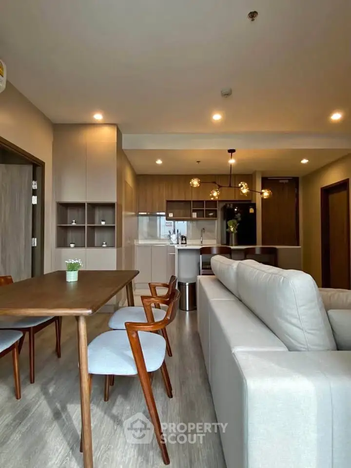Modern open-layout living room with stylish furniture and kitchen area, perfect for contemporary living.