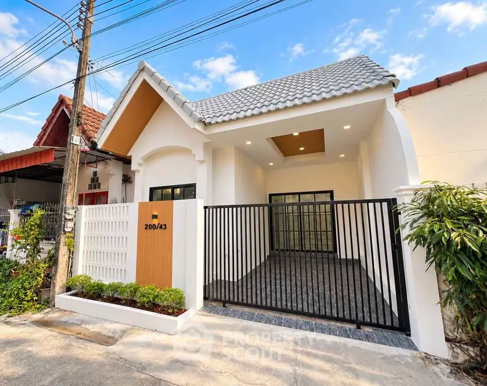 Charming single-story house with modern facade and gated driveway in a peaceful neighborhood.