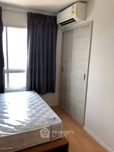 Cozy bedroom with natural light, featuring a sliding closet and air conditioning.