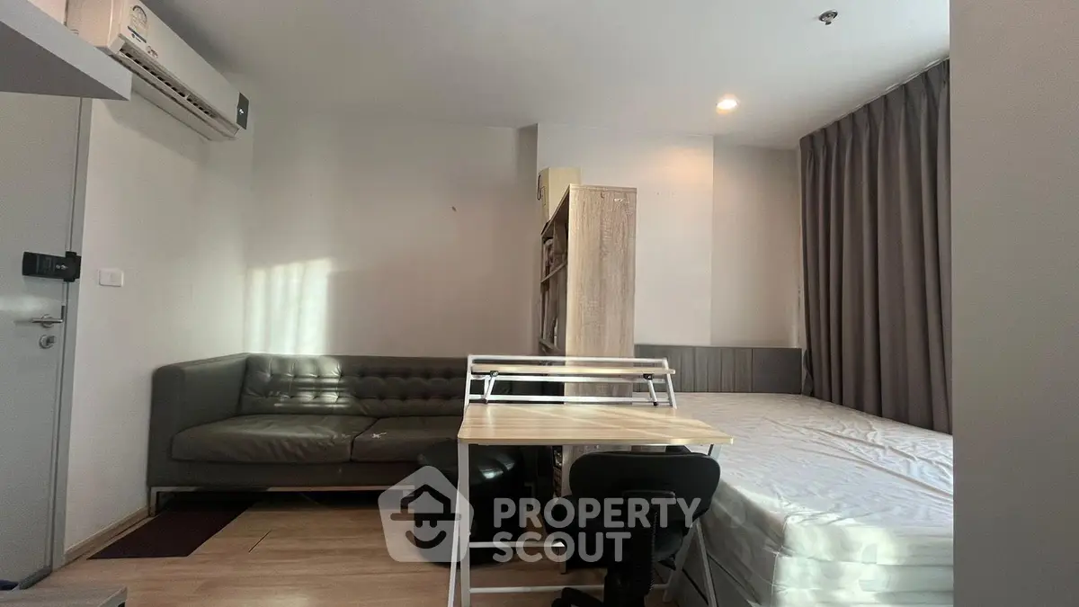 Modern studio apartment with cozy living area and bed, featuring sleek furniture and ample natural light.