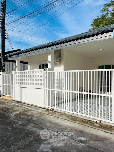 Charming single-story home with white fence and spacious front patio.