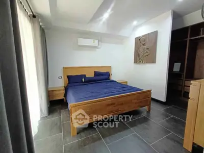 Modern bedroom with wooden furniture and stylish decor, featuring a comfortable bed and ample natural light.