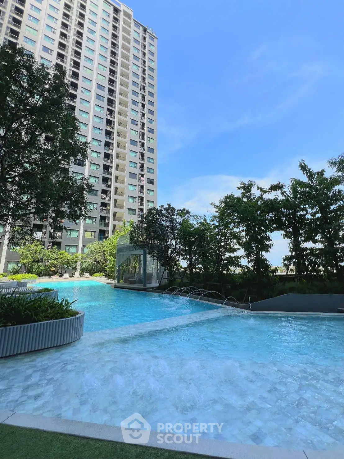 Luxurious high-rise building with stunning pool and lush greenery, perfect for modern living.