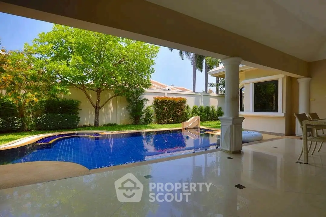Luxurious private pool with lush garden view in elegant villa setting.