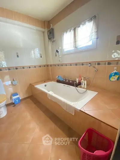 Spacious bathroom with a large bathtub and natural light.