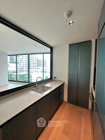 Modern kitchen with sleek cabinetry and city view, featuring open layout and elegant design.
