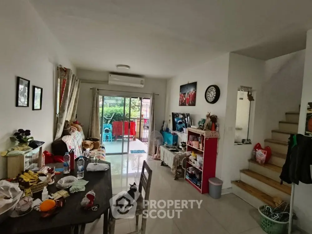 Cozy living room with dining area and balcony access, featuring modern decor and natural light.