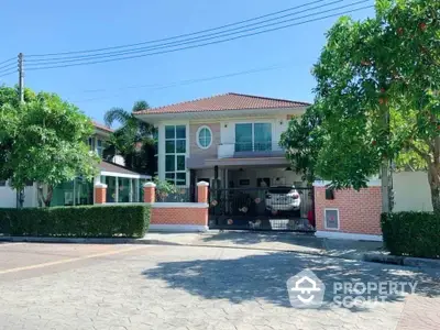 Charming two-story house with lush greenery and spacious driveway