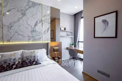 Modern bedroom with elegant decor and study area, featuring marble accents and natural light.