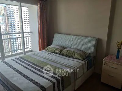 Cozy bedroom with large window offering city view, featuring a comfortable bed and stylish decor.