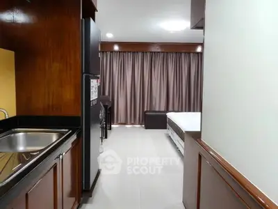 Spacious studio apartment with modern kitchen and cozy living area, featuring elegant wooden cabinetry and ample natural light.