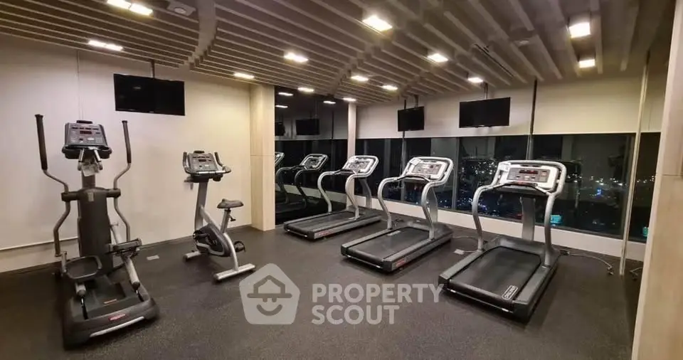 Modern gym with treadmills and exercise bikes in a high-rise building.
